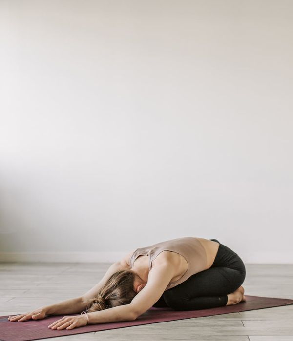 Person practicing gentle yoga movements in a dark modern studio